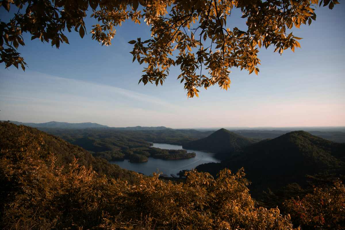 Scenic view of mountains and a winding lake under a clear sky, representing peaceful recovery and online addiction treatment in Tennessee.