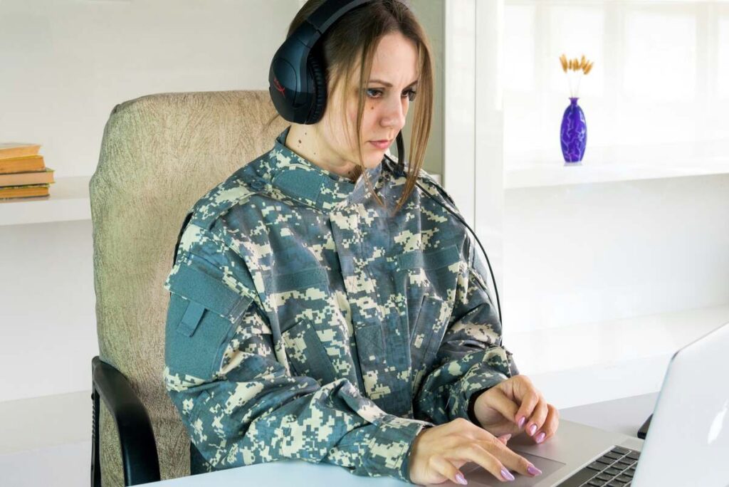 Soldier in uniform attending an online rehab session through a laptop, representing virtual addiction treatment for veterans.