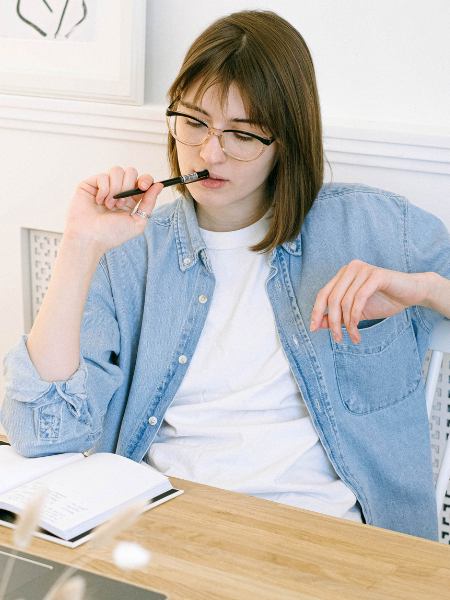 A woman sitting at home, taking notes to determine which mental health programs she may need