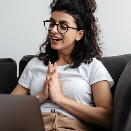 A young woman sitting on a couch and smiling during a therapy session online