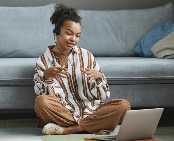 A young woman sitting in front of a couch during a video call for mental health therapy