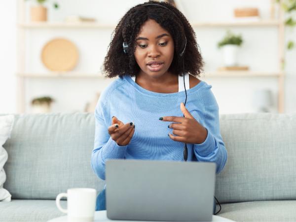 A young woman sitting on a couch and having a video call for rehab therapy