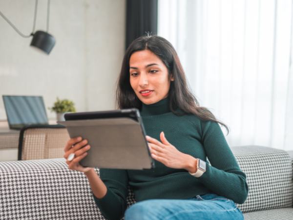 A woman sits at home using her tablet for a telemental health visit