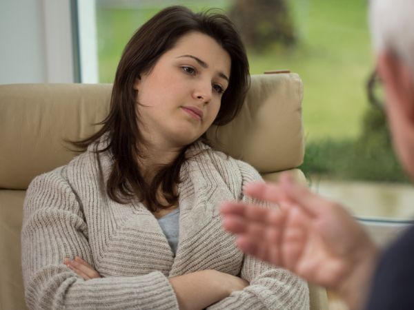 A woman sits and listens to a therapist during an individual mental health session