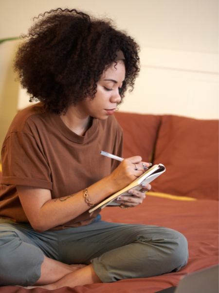 A woman sitting at home and taking notes about her mental health therapy needs