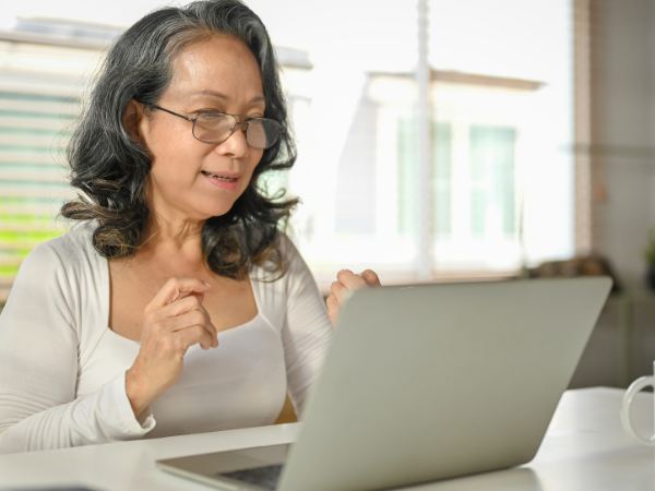 A senior woman sitting at home using a laptop during virtual mental health treatment