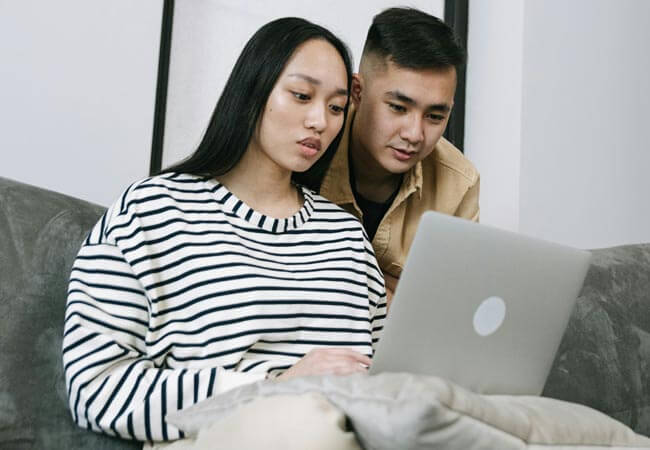 A couple share a laptop for an online mental health session