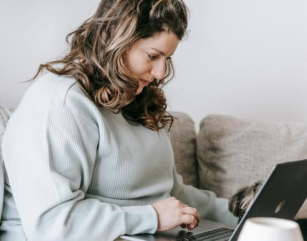 Woman sitting at home with her dog next to her laptop during a remote therapy session