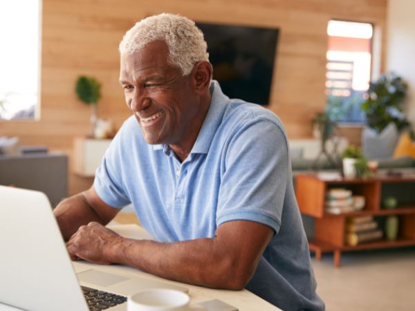 A senior man uses a laptop for online substance addiction rehab for the elderly