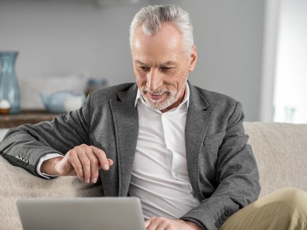 An executive sits on a couch while using a laptop for mental health therapy
