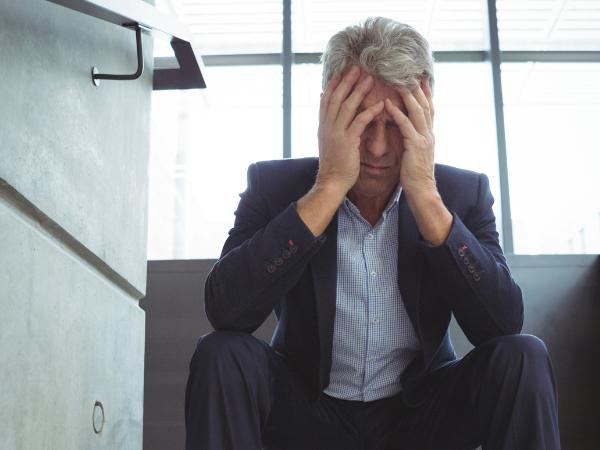 A businessman struggling with addiction sits alone on the stairs inside a building