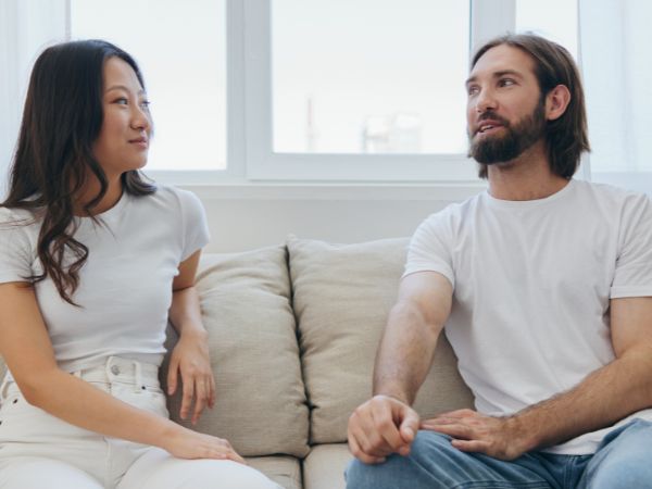 A woman and man sitting on a couch talking about rehab
