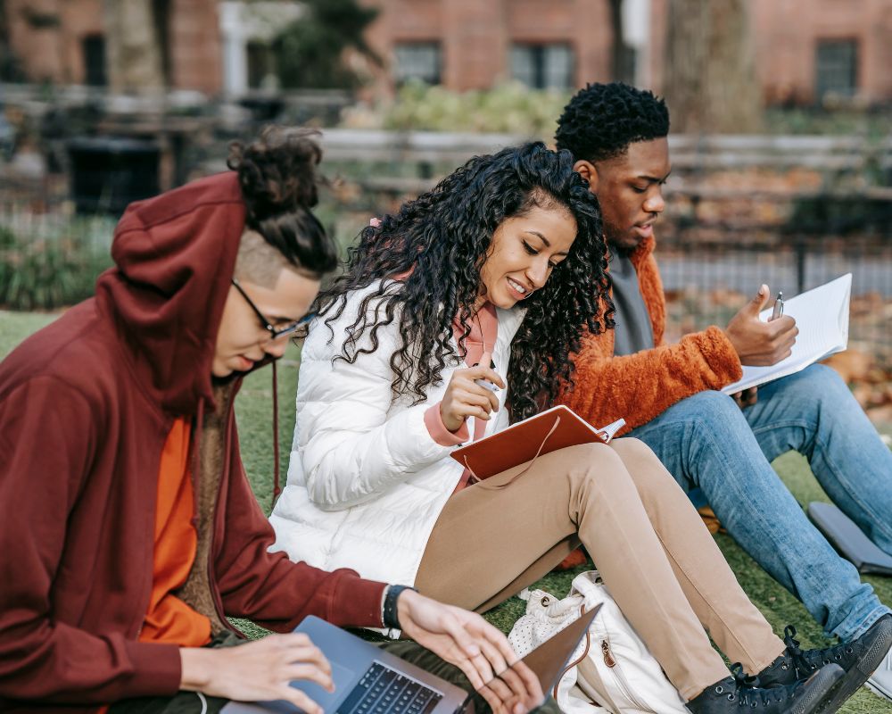 Three university students sitting outdoors and studying