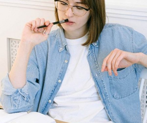 A woman sitting at home, taking notes to determine which mental health programs she may need