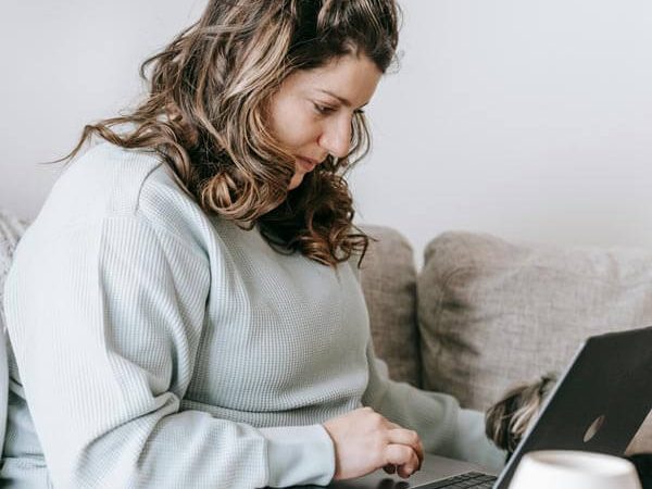 Woman sitting at home with her dog next to her laptop during a remote therapy session