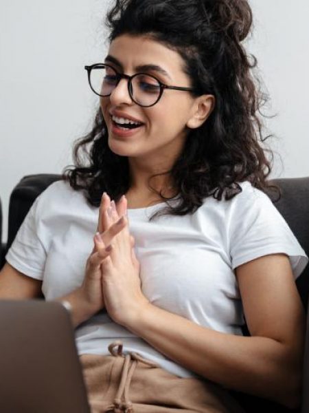 A young woman sitting on a couch and smiling during a therapy session online